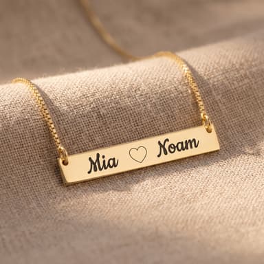 Macro of engraved names on a heart-bar pendant, crisp legible engraving