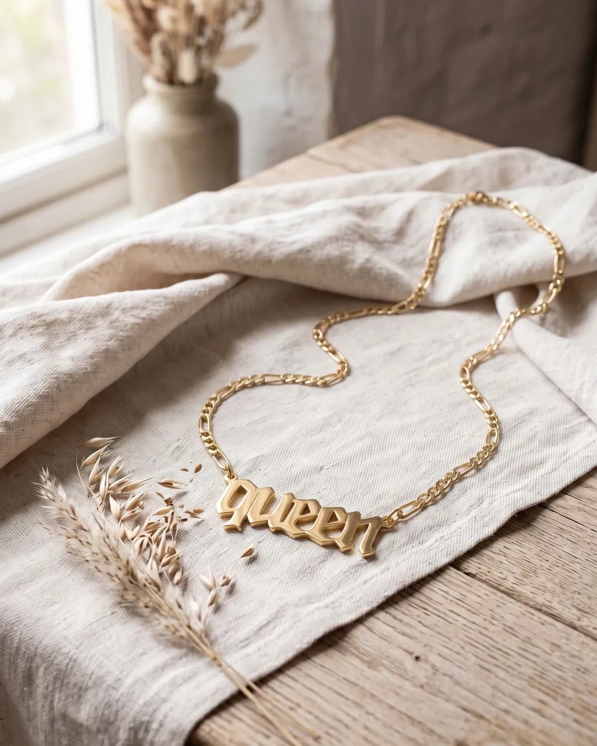 A gold plated “Queen” necklace on ivory linen