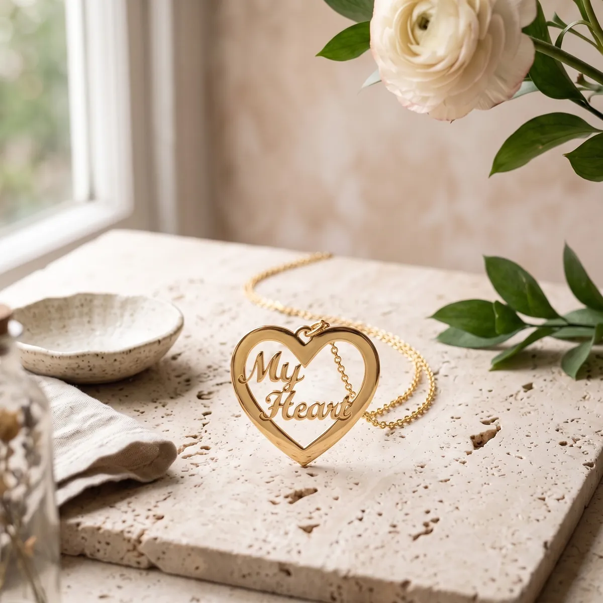 A gold plated “My Heart” necklace on pale travertine